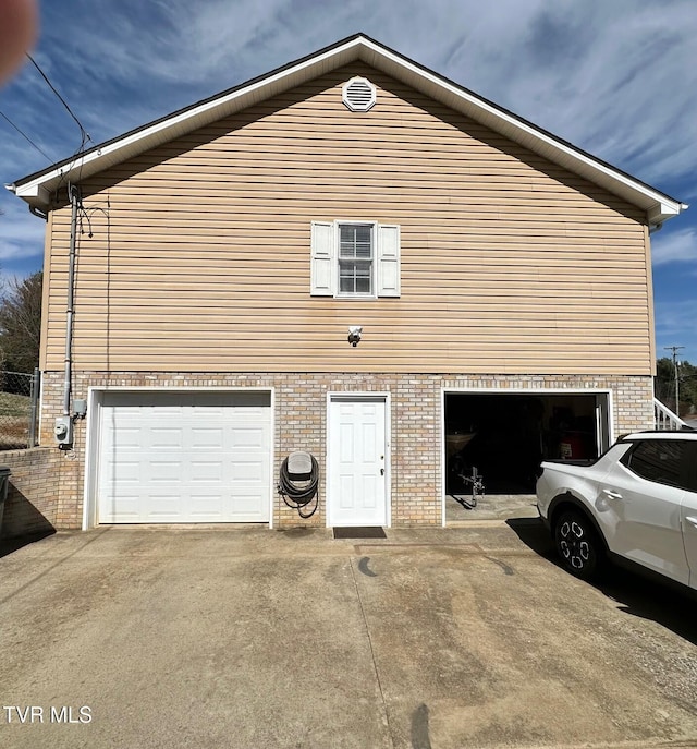 view of property exterior featuring brick siding, concrete driveway, and a garage