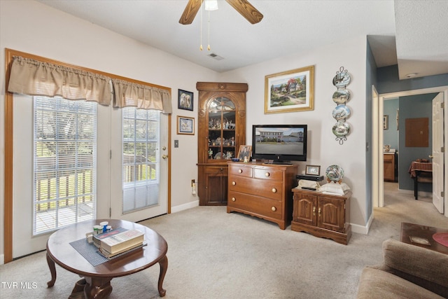 living area with visible vents, baseboards, light colored carpet, and ceiling fan