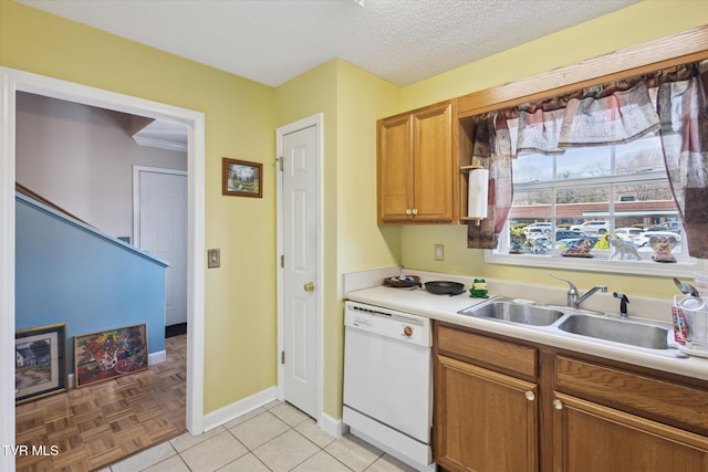 kitchen featuring dishwasher, light countertops, brown cabinetry, a textured ceiling, and a sink