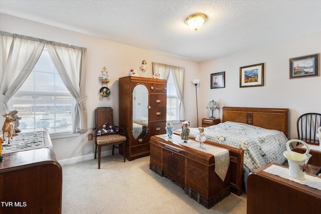 bedroom with light colored carpet, baseboards, and a textured ceiling