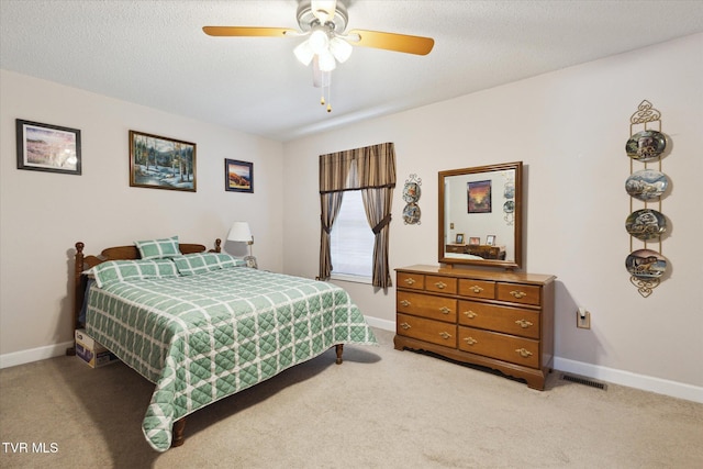 bedroom featuring light carpet, visible vents, a textured ceiling, and baseboards