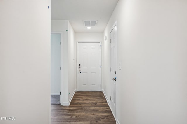 hall featuring visible vents, dark wood-type flooring, and baseboards