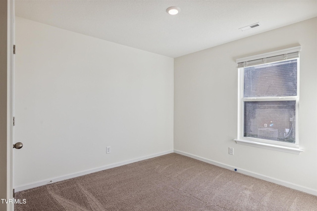 carpeted spare room with visible vents and baseboards