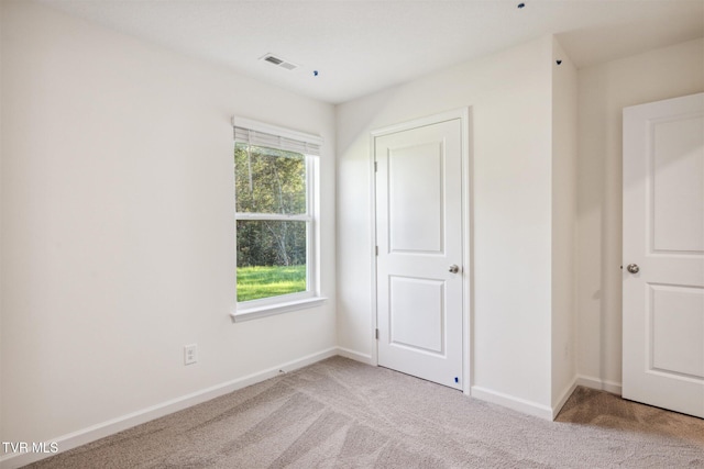 unfurnished bedroom featuring baseboards, light carpet, and visible vents