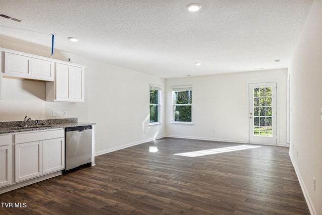 kitchen with dark wood-type flooring, dark stone countertops, stainless steel dishwasher, white cabinets, and a sink