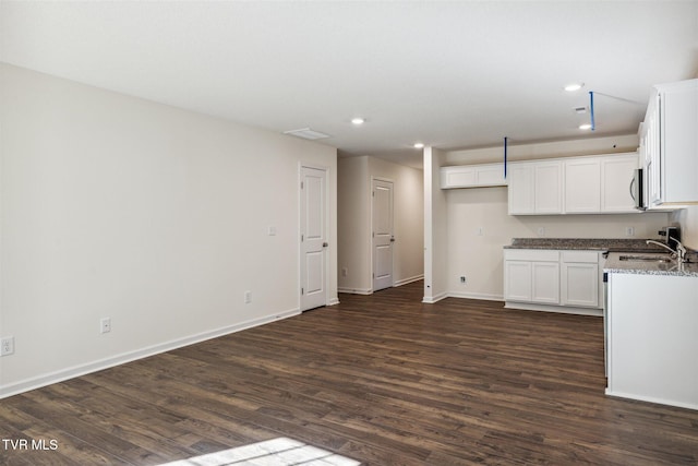 kitchen featuring stainless steel microwave, dark wood finished floors, recessed lighting, white cabinets, and baseboards