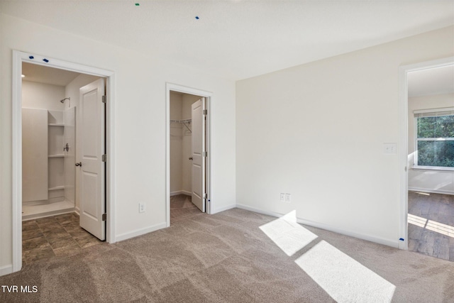 unfurnished bedroom featuring a walk in closet, carpet, a closet, and baseboards