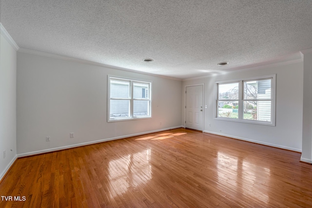 unfurnished room featuring baseboards, a healthy amount of sunlight, wood finished floors, and crown molding