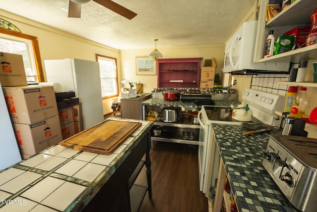 kitchen with dark wood finished floors, tile countertops, ceiling fan, and white appliances