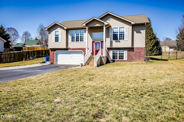 bi-level home featuring aphalt driveway, a front lawn, brick siding, and fence