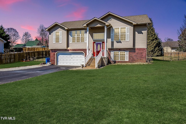 raised ranch with aphalt driveway, brick siding, and fence