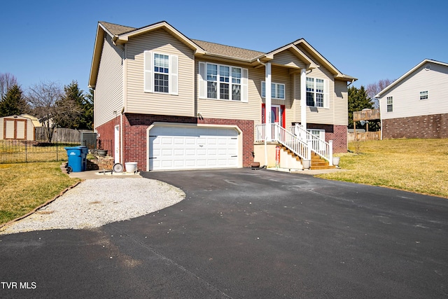 split foyer home with aphalt driveway, brick siding, a front lawn, and fence