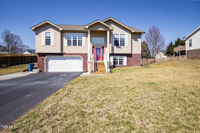 bi-level home featuring brick siding, fence, a front yard, a garage, and driveway