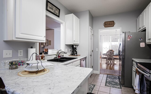 kitchen featuring light tile patterned floors, white cabinetry, electric stove, and a sink