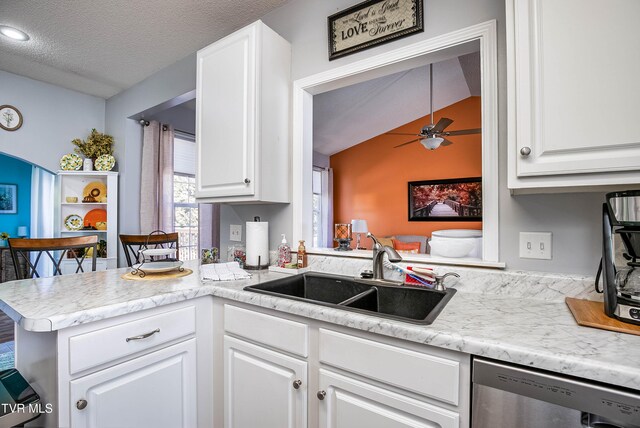 kitchen featuring a sink, a peninsula, white cabinetry, and stainless steel dishwasher