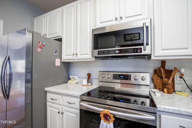 kitchen featuring white cabinetry, light stone countertops, backsplash, and stainless steel appliances