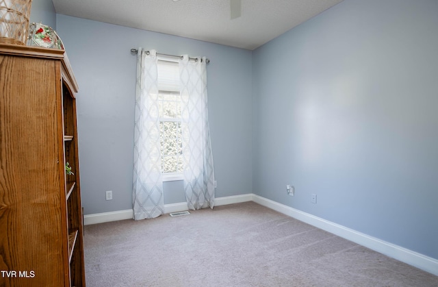 empty room featuring baseboards, visible vents, carpet floors, and a textured ceiling