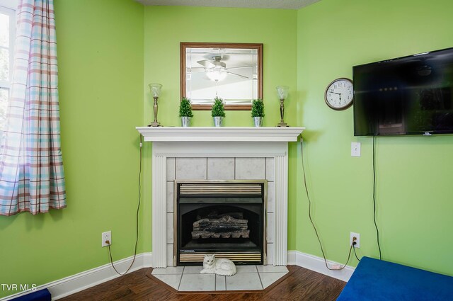 room details featuring a tiled fireplace, wood finished floors, and baseboards