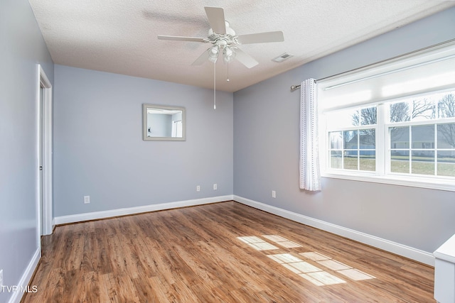 unfurnished room with visible vents, a textured ceiling, baseboards, and wood finished floors