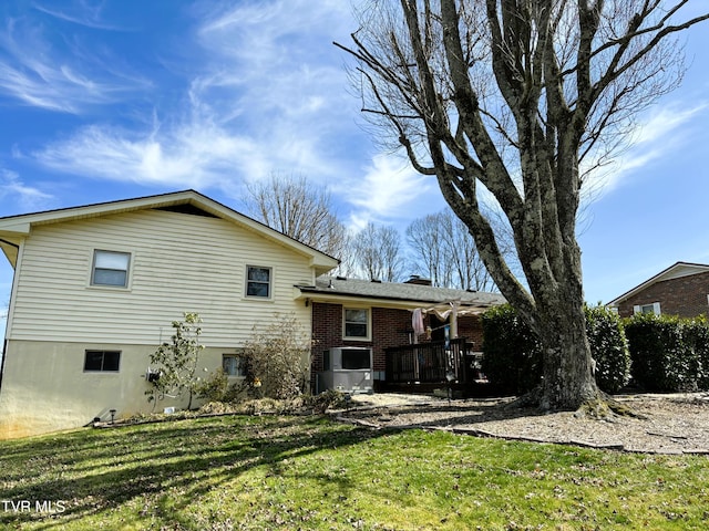 rear view of property featuring a yard, brick siding, and a chimney