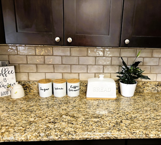 interior details featuring dark brown cabinets, backsplash, and light stone countertops