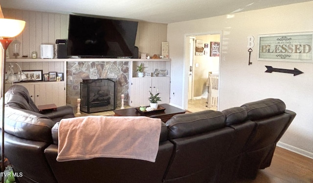 living area featuring a stone fireplace, wood finished floors, and baseboards