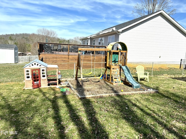 view of jungle gym featuring an outbuilding, a storage shed, a yard, and fence