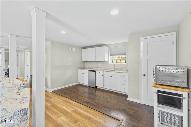 kitchen featuring white cabinets, wood finished floors, baseboards, and a sink