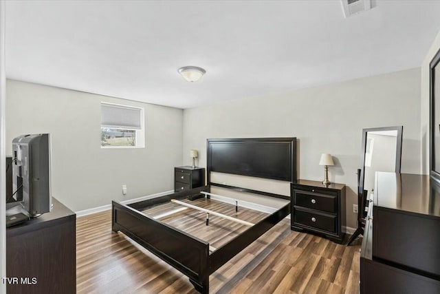 bedroom with dark wood-style floors, visible vents, and baseboards