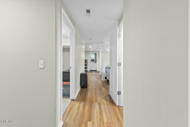 hall with light wood-style floors, visible vents, and baseboards