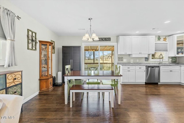 kitchen featuring light stone counters, stainless steel dishwasher, dark wood-style floors, white cabinets, and a chandelier