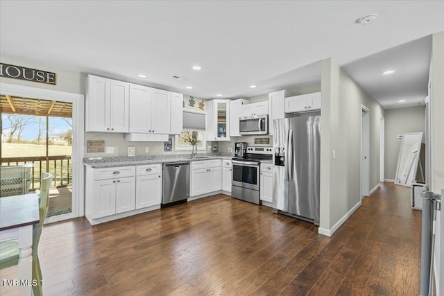 kitchen with stainless steel appliances, light stone countertops, dark wood-type flooring, and plenty of natural light