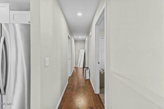 corridor with dark wood finished floors and baseboards