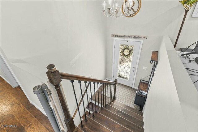 staircase featuring hardwood / wood-style floors, baseboards, and a chandelier