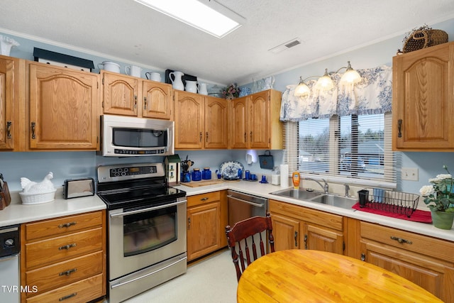 kitchen with appliances with stainless steel finishes, light countertops, and a sink