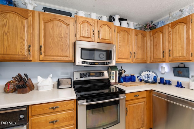 kitchen with a textured ceiling, light countertops, brown cabinetry, and stainless steel appliances