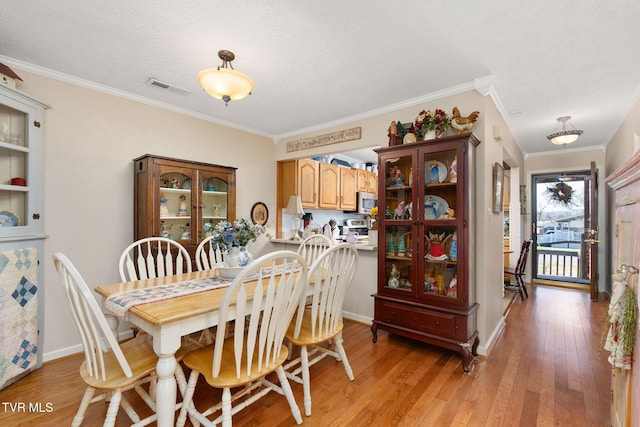 dining room featuring crown molding, light wood-style floors, and visible vents