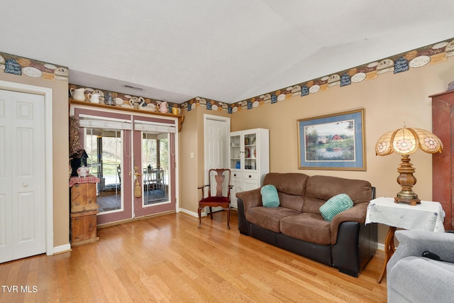 living area with light wood finished floors, visible vents, baseboards, lofted ceiling, and french doors