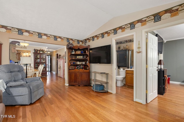 living area with light wood-style flooring, baseboards, lofted ceiling, and ornamental molding