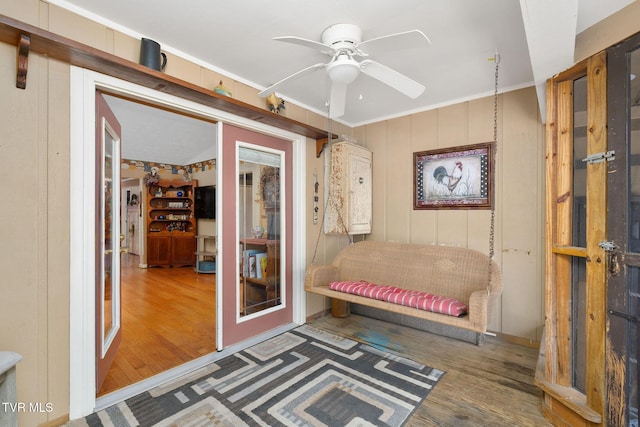 sitting room featuring ornamental molding, a ceiling fan, and wood finished floors