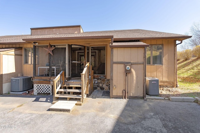 view of front of property featuring central AC unit and roof with shingles