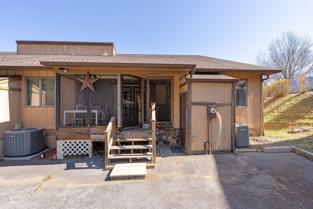 exterior space featuring central AC and a shingled roof