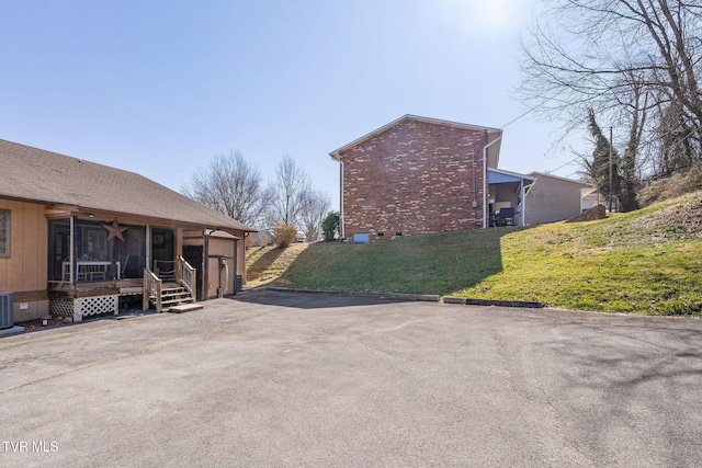 view of property exterior featuring a yard, a garage, crawl space, central air condition unit, and brick siding