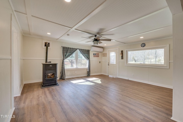 unfurnished living room featuring recessed lighting, a wall mounted air conditioner, a wood stove, and wood finished floors