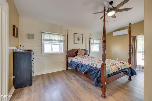 bedroom with lofted ceiling, multiple windows, wood finished floors, and a wall mounted air conditioner