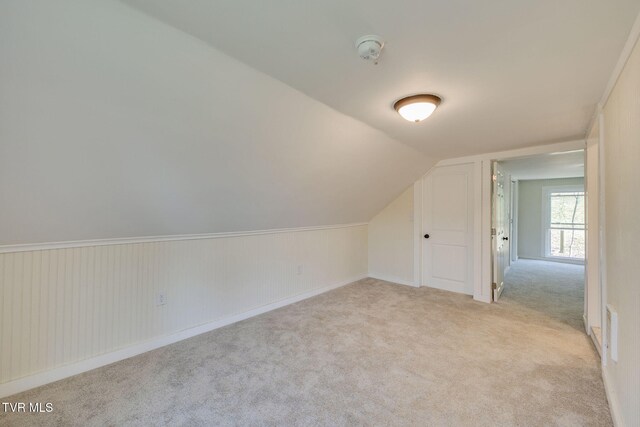 additional living space with light carpet and vaulted ceiling