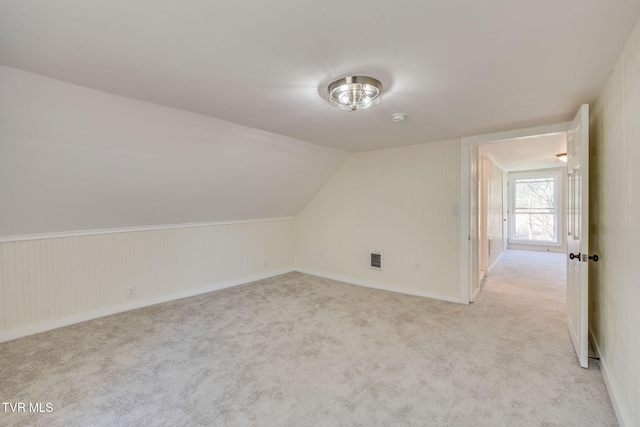 additional living space featuring visible vents, light carpet, and vaulted ceiling