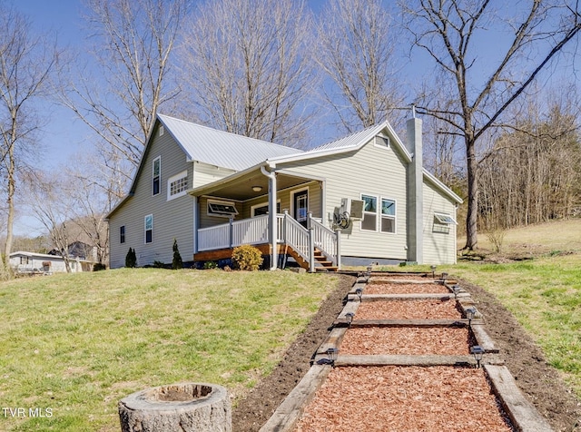 view of front of house with a front lawn, metal roof, covered porch, and a chimney