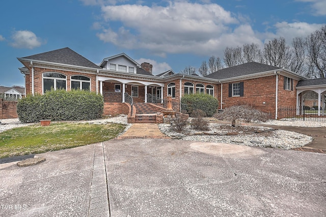 view of front of home featuring brick siding, covered porch, a chimney, and a shingled roof