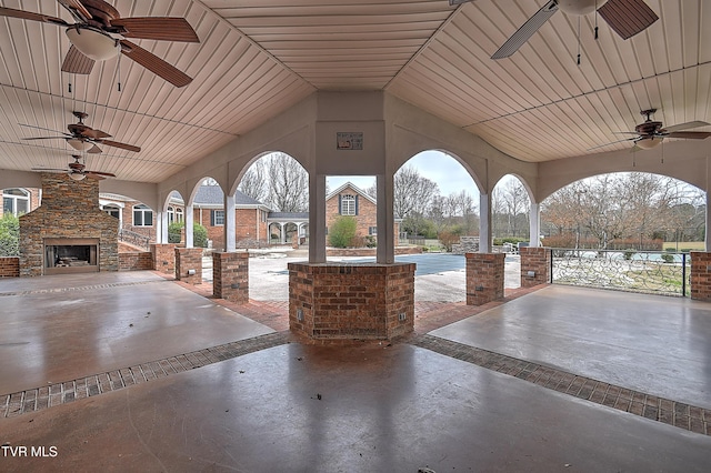 view of patio with an outdoor stone fireplace and ceiling fan